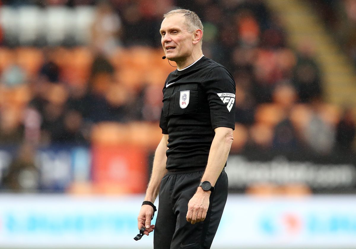 Premier League official preparing a substitution board during a match